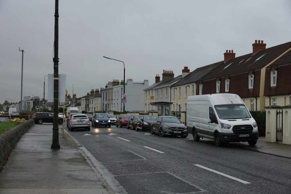 Cars are driving on a road next to houses