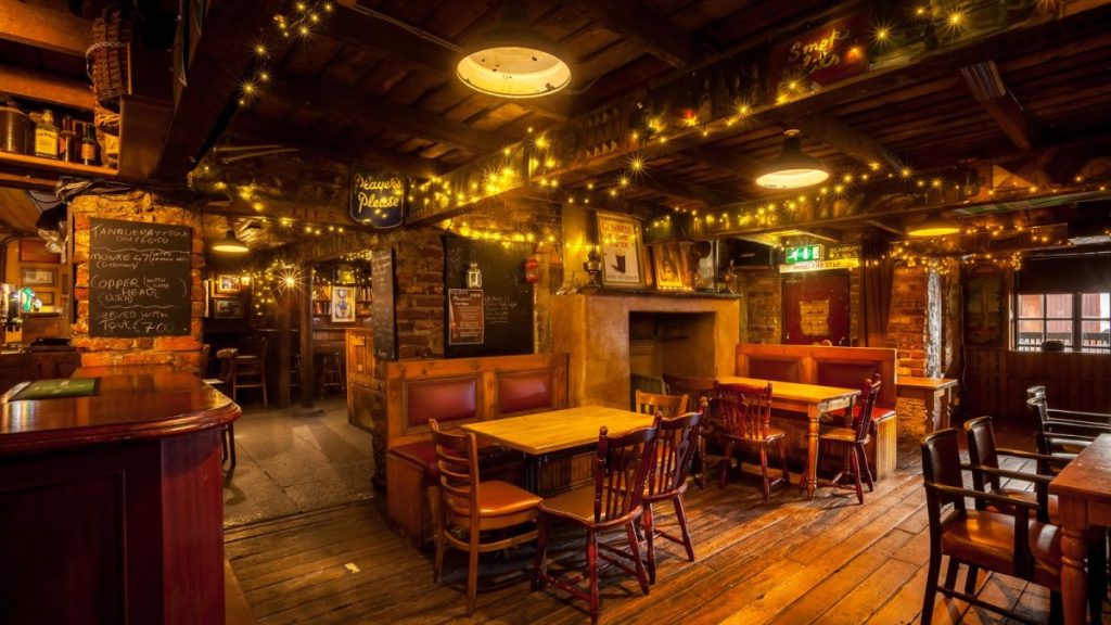 Warmly lit traditional Irish pub interior with wooden furniture and fireplace