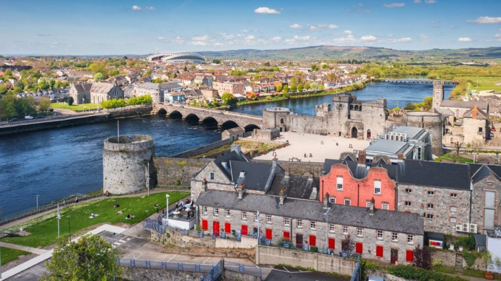Medieval castle and fortifications beside river in Irish town landscape