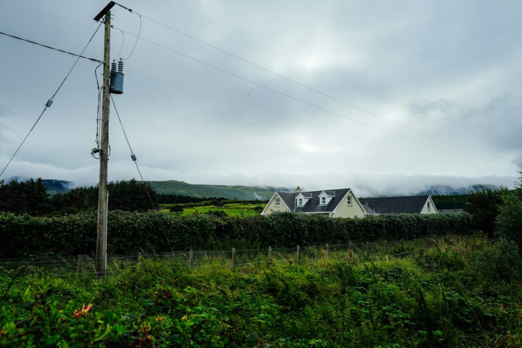 Three houses behind a hedge on a cloudy day