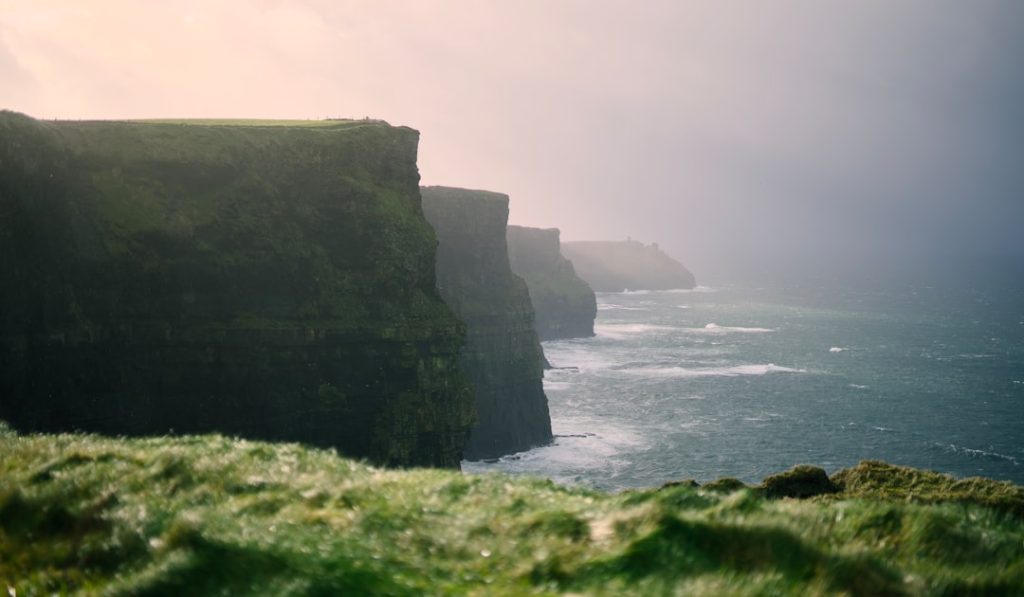 A person standing on the edge of a cliff overlooking the ocean