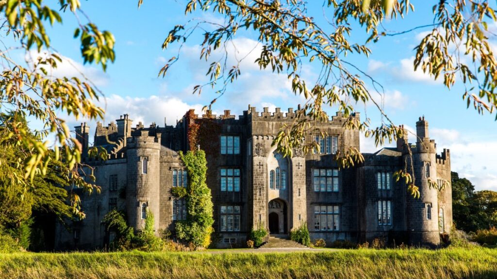 Medieval stone castle with ivy-covered walls and manicured grounds under autumn sky