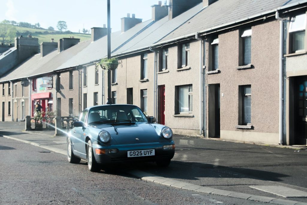 A blue sports car parked on a quiet street lined with terraced houses